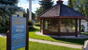 photo of the glassed-in enclosure of the world's largest ball of twine, along with a faded sign discussing the creation of the twine ball and measurements